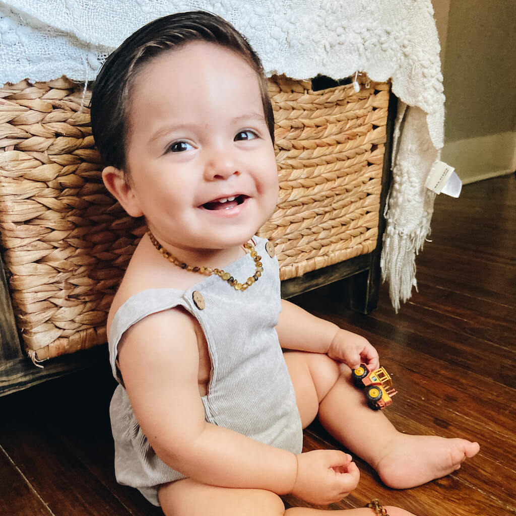 Teething Baby Boy Wearing Premium Baltic Amber Necklace and Anklet in Green Colors with Raw/Unpolished Beads, Made by Amber Guru, Sitting in the Room