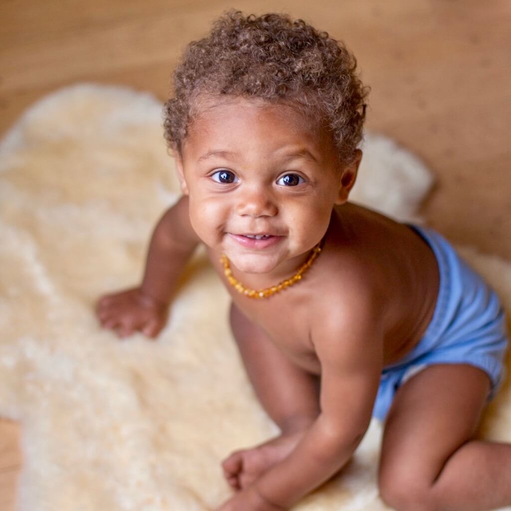 African American Baby Boy with Curly Hairs, Wearing Premium Baltic Amber Teething Necklace in Honey Color with Polished Beads, Made by Amber Guru
